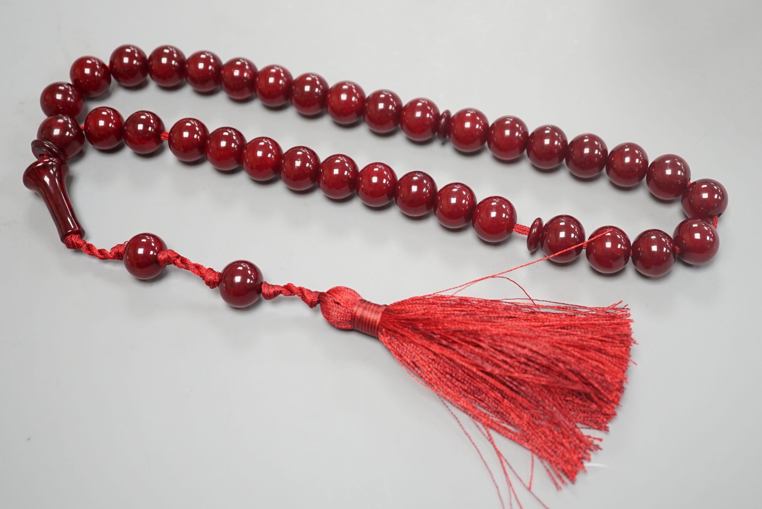 A single strand cherry amber bakelite necklace, 92cm including tassel, gross weight 88 grams.